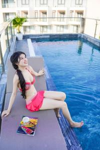 岘港Sea Wind Hotel by THG的坐在游泳池旁的红比基尼的女人