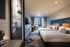 墨尔本Dorsett Melbourne的酒店客房配有两张床和一张书桌