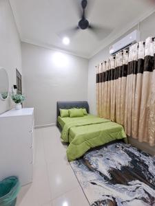 JeliHomestay Jeli - Cattleya Inn Muslim的一间卧室配有绿色的床和窗帘