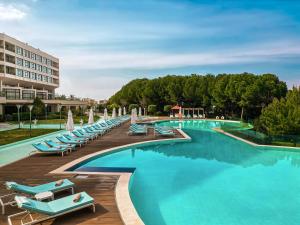 伊兹密尔伊兹密尔卡亚温泉&会议中心酒店的一座带蓝色躺椅的游泳池以及一座建筑
