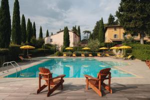 蒙泰斯佩尔托利Villa La Cappella的一个带两把椅子和遮阳伞的游泳池