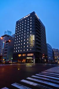 名古屋多美迎PREMIUM名古屋荣酒店的夜幕降临的城市街道上一座高大的黑色建筑