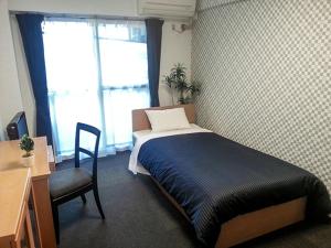 府中市HOTEL LiVEMAX BUDGET Fuchu的一间卧室配有一张床、一张桌子和一把椅子