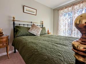特维德上游的贝里克18 Mill Wharf Apartment的一间卧室设有一张绿色的床和一个窗户。