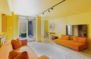 伦敦189A Caledonian Road, London, N1 0SL的客厅配有橙色沙发和电视