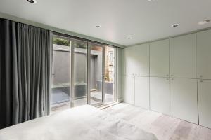 伦敦189A Caledonian Road, London, N1 0SL的卧室配有白色橱柜和大窗户