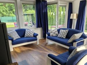 策德尼克Ferienhaus Am See 19的客厅设有2张蓝色的沙发和窗户。