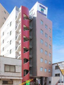 府中市HOTEL LiVEMAX BUDGET Fuchu Annex的一座高大的红色建筑,上面有标志