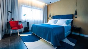 里斯本Hills Hotel Lisboa的一间卧室配有蓝色的床和红色椅子