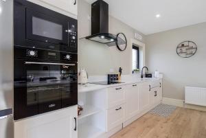 TieveborneSeaview Lodge Apartment 'Sleeping 4 Guests'的厨房配有白色橱柜和黑烤箱。