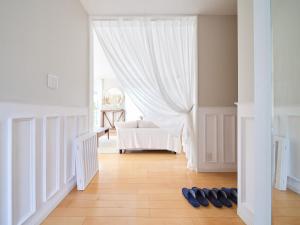 横须贺市Villa OLIVE Sajima -佐島の丘- ペット可的一间铺有白色窗帘和鞋子的客房