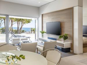 开普敦South Beach Camps Bay Boutique Hotel的客厅配有桌椅和平面电视。