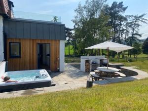 NewburghLuxury Lodge with Hot Tub at Lindores的一座带热水浴缸、桌子和雨伞的建筑