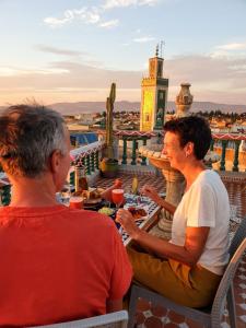 梅克内斯里亚德马拉克酒店的两个人坐在大楼屋顶的桌子上