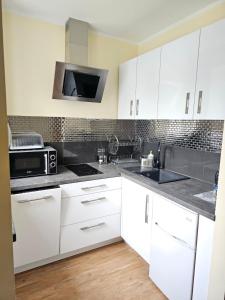 斯维诺乌伊希切Lazur Apartamenty的厨房配有白色橱柜和微波炉