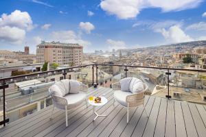 热那亚贝斯特韦斯特PLUS城市酒店的阳台配有两把椅子和一张桌子,位于屋顶
