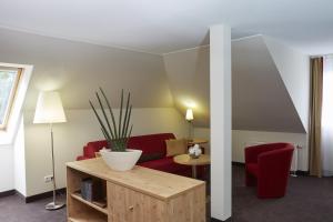 腓特烈罗达腓特烈罗达H+水疗酒店的客厅配有红色的沙发和桌子