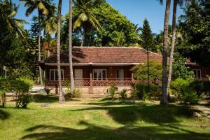 哥印拜陀Ibex River Resort, Pollachi的前面有棕榈树的房子