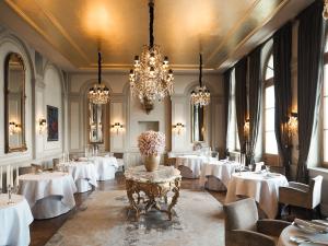 巴塞尔Grand Hotel LES TROIS ROIS的一间设有白色桌子和吊灯的用餐室