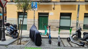 马德里Malasaña Dreams S,L的一群停在街上的摩托车,上面有一把伞