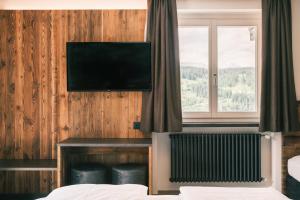 塞尔瓦迪加尔代纳山谷Kristiania Small Dolomites Hotel的酒店客房的墙上配有平面电视