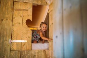 桑特佩尔佩斯卡多尔Camping Sènia Riu的坐在木房子床边的小女孩