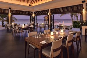 丹格迪Nova Maldives的餐厅设有桌椅,以大海为背景