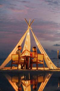 丹格迪Nova Maldives的坐在帐篷下桌子上的男女