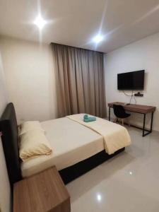 古晋Kuching Kozi Square Apartment (II)的一间卧室配有一张床、一张书桌和一台电视