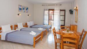 尼欧克利马Aris Junior Studios Neo Klima Skopelos的酒店客房带两张床、一张桌子和一间餐厅