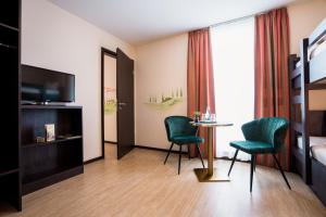 灵斯海姆Hotel La Toscana Nähe Europapark的酒店客房带一张床、一张桌子和椅子