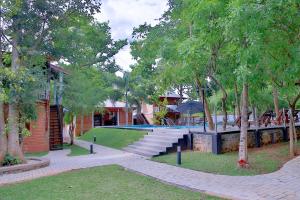 锡吉里亚Tepraas Sigiriya的一座公园,公园里设有游泳池和树木,还有一座建筑