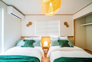 冲绳岛市SHIOYA STAY的一间卧室配有两张绿色和白色的床