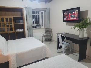 麦德林New Memphis Hostal的一间卧室配有两张床和一张书桌及电视