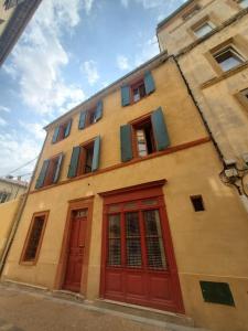 纳博讷La Louve - maison de ville的街道上设有红色门窗的建筑