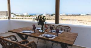 TagouGaia Mykonos Villas & Suites的一张带椅子的木桌,享有海滩美景
