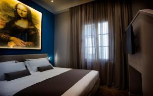 佛罗伦萨The Frame Hotel的卧室配有一张带女性绘画的床