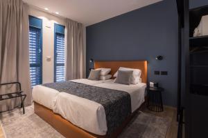 耶路撒冷AMALON Boutique Apartments的一间卧室设有一张大床,拥有蓝色的墙壁和窗户。