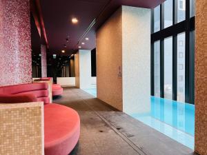 墨尔本Sweet Home Apartment Melbourne CBD的大堂设有粉红色的椅子和一座游泳池
