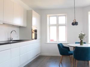 斯瓦讷克Holiday home Svaneke XLI的厨房配有白色橱柜和桌椅