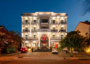 会安Silkian Hoian Boutique Hotel & Spa的一座白色的建筑,前面有汽车停放