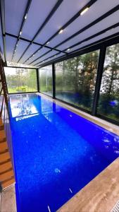 萨潘贾Emela Villa的一座大型蓝色游泳池,位于带窗户的建筑内