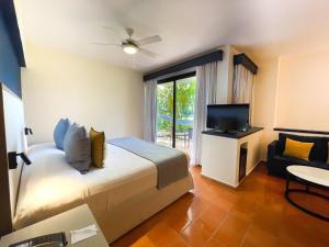 蓬塔卡纳蓬塔卡纳加泰罗尼亚全包酒店的一间卧室配有一张床、一台电视和一把椅子