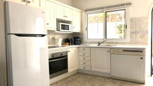 科斯塔卡玛Top Seaside Powered by SolymarCalma的厨房配有白色橱柜和白色冰箱。
