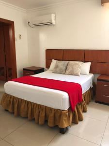 瓜亚基尔Hoteles en Guayaquil - Suites Guayaquil Cerca del Aeropuerto的一间卧室配有一张带红色毯子的大床