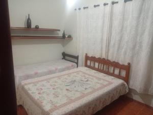 乌贝拉巴Casa Lá Vita的带窗帘的客房内的两张单人床