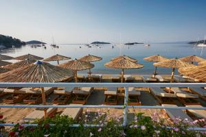 斯基亚索斯镇Skiathos Ammos Luxury Apartments的海滩上的一组椅子和遮阳伞