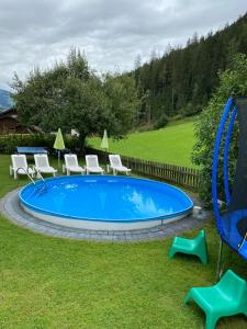 平茨高谷地霍勒尔斯巴赫霍奇维梅尔旅馆的庭院内的游泳池配有椅子和秋千