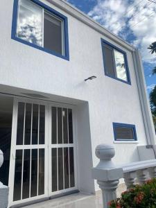 里考尔特Amazing Home Ricaurte-Casa verano piscina-Aire acondicionado的白色的房子,有蓝色的窗户和门
