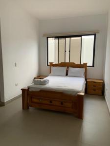 OibaHotel Hacienda Guane Urbano的一间卧室配有一张木床和窗户